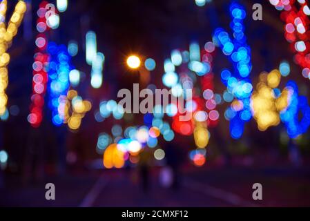 Luci di strada sfocate e ghirlande festive sulla strada a. notte Foto Stock