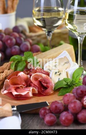 Antipasto. Spuntini a base di vino di prosciutto secco, formaggio camembert con muffa, parmigiano con grissini, olive Foto Stock