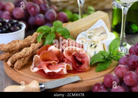 Antipasto. Spuntini a base di vino di prosciutto secco, formaggio camembert con muffa, parmigiano con grissini, olive Foto Stock