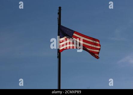 Una Bandiera americana che svetta nella brezza del molo di Kure Beach sullo sfondo di un cielo blu Carolina. Foto Stock