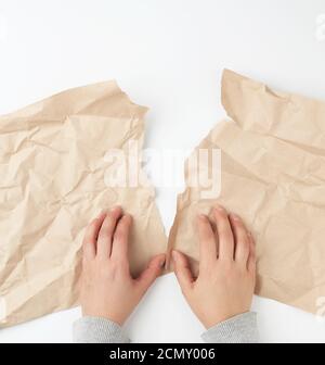 due mani che strappano un foglio di carta da mestiere marrone Foto Stock