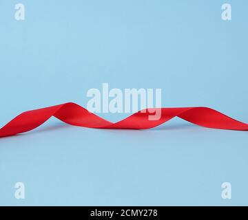 sottile nastro di seta rosso su sfondo blu Foto Stock