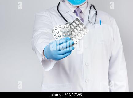 il medico terapeuta adulto è vestito con un cappotto bianco uniforme e guanti sterili blu è in piedi e ho Foto Stock