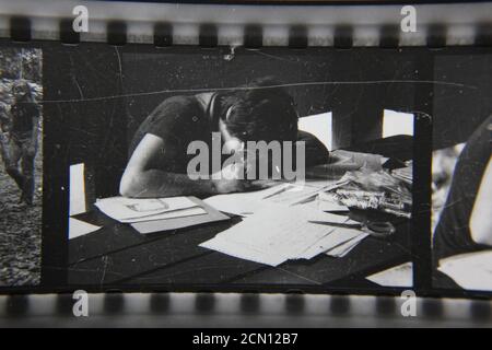 Fine 1970 vintage fotografia in bianco e nero di scout campeggio al campo estivo scout e una donna che scrive a mano un mazzo di documenti. Foto Stock