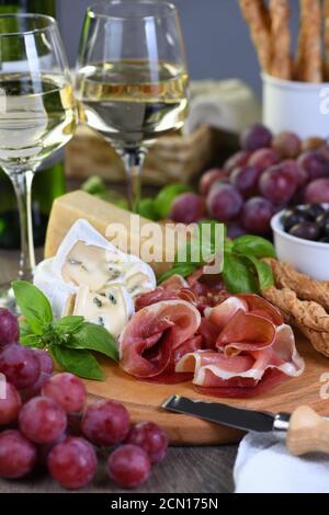 Antipasto. Spuntini a base di vino di prosciutto secco, formaggio camembert con muffa, parmigiano con grissini, olive Foto Stock