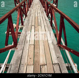 Primo piano su passerella in legno con arrugginito guardrail su acque turchesi Foto Stock