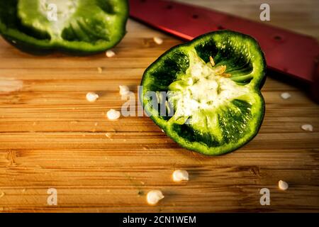 Dettaglio del pepe a fette sulla tavola da taglio di bambù successivo a semi e coltello Foto Stock