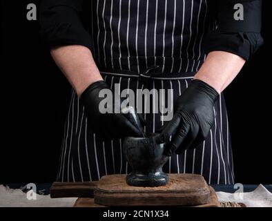 chef uomo che tiene un mortaio di pietra e pestello per macinare spezie Foto Stock