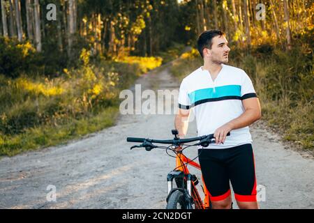 Sportswear giovane uomo che spinge la bicicletta in montagna Foto Stock