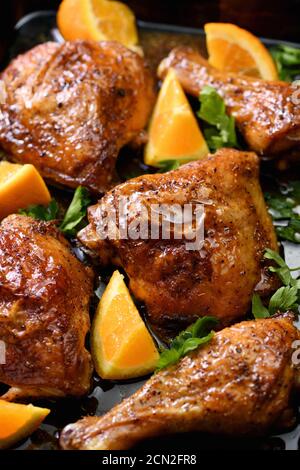 fette appetitose di pollo al forno con crosta fritta croccante e arance in una teglia Foto Stock