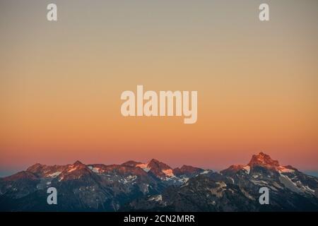 Alpenglow sulla catena montuosa più lontana. Foto Stock