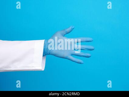 medic in un cappotto bianco, i guanti di lattice blu tira la mano per una stretta di mano Foto Stock