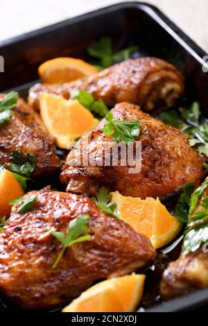 fette appetitose di pollo al forno con crosta fritta croccante e arance in una teglia Foto Stock