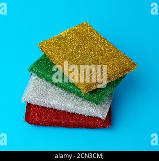pila di nuove spugne multicolore da cucina per lavare le stoviglie uno sfondo blu Foto Stock