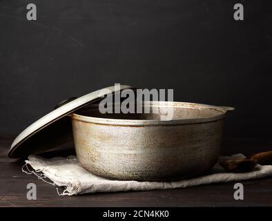 vecchio calderone in alluminio su un tavolo in legno, utensili da cucina Foto Stock