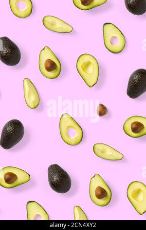 Avocado. Sfondo realizzato con pezzi di avocado isolati su sfondo rosa. Piatto di avocado fresco maturo e pezzi di avacado. Foto Stock