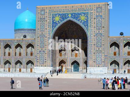 Turisti che visitano il Registan a Samarkand con Tilya-Kori Madrasa (madrassah) alle spalle. Turismo in Uzbekistan. Tour dei visitatori di gruppo. Foto Stock