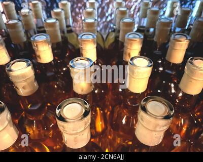 Primo piano di bottiglie di vino bianco con tappi presso l'azienda vinicola locale - vino tradizionale fatto in casa o bevande alcoliche a base di frutta in un negozio di vini locale. Bottiglie di vino senza Foto Stock