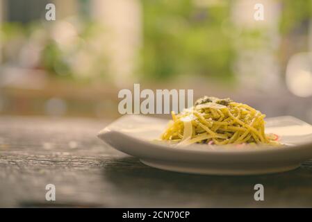 Spaghetti con salsa al pesto contro tavola di legno Foto Stock