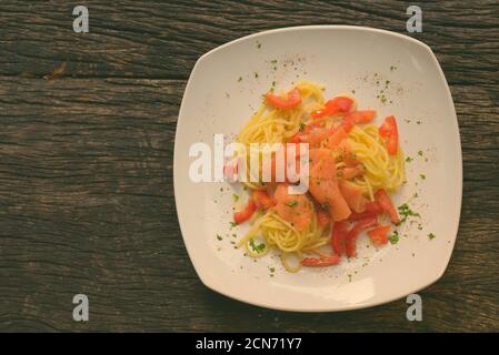 Spaghetti al salmone con pomodoro fresco contro tavola di legno Foto Stock