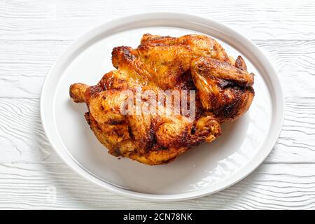 pollo arrosto servito su un piatto bianco su un tavolo di legno, vista orizzontale dall'alto, primo piano Foto Stock