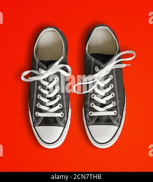 Sneakers nere isolate su sfondo rosso Foto Stock