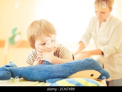 Medico che fa massaggio delle gambe ad un bambino su un lettino medico Foto Stock