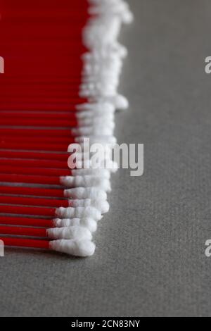 Bastoncini di cotone su bastoncini rossi, fondo grigio Foto Stock