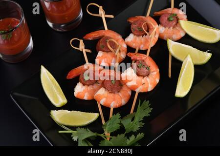 Antipasto di shish kebab con gamberi e chorizo salsicce con salsa barbecue in un bicchiere Foto Stock