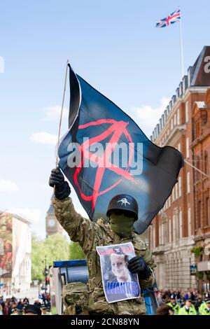 Un dimostratore anti austerità ha una bandiera di anarchia, protestando contro il nuovo governo conservatore e la loro politica di austerità, Whitehall, Westminster, Londra, Regno Unito. 9 maggio 2015 Foto Stock