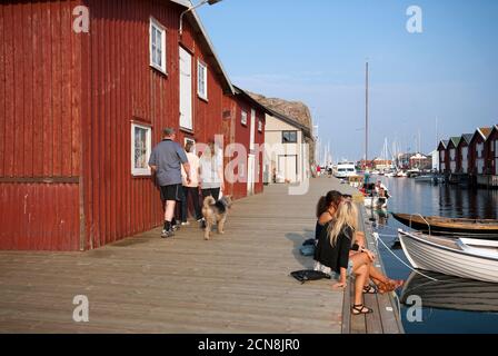 Persone che camminano e giovani donne che siedono sul molo di legno a Sorgen, Västra Götaland contea, Svezia Foto Stock