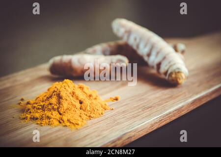 Radice curcuma e polvere di spezie su un tagliere Foto Stock