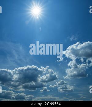 Alcune nuvole leggere cumuliformi e il Sole sopra di loro nel cielo azzurro pulito. Natura sfondo. Foto Stock