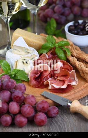Antipasto. Spuntini a base di vino al prosciutto, formaggio brie con muffa, parmigiano con grissini, olive e p. Foto Stock