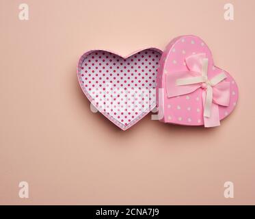 aprire una scatola di cartone rosa vuota sotto forma di cuore su sfondo beige Foto Stock