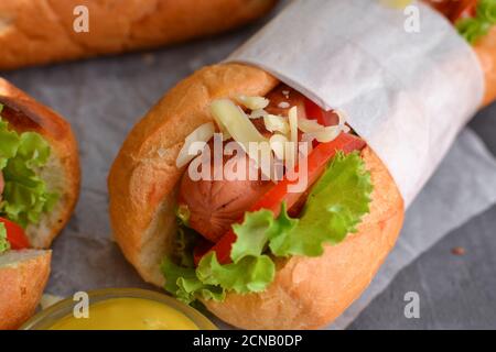 Hot dog con vari riempimenti. Sfondo scuro. Cibo sfondo con spazio di copia. Hot dog con senape e ketchup, lattuga, formaggio e pomodori Foto Stock