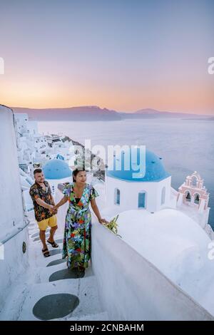 Santorini Grecia, giovane coppia in vacanza di lusso sull'isola di Santorini guardando l'alba dalla chiesa blu a cupola e whitew Foto Stock