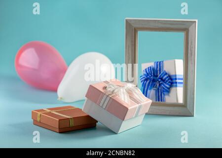 Composizione con cornice fotografica, scatole regalo e palloncini. Foto Stock