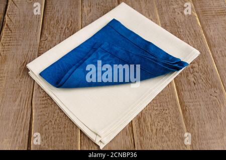 primo piano di tovaglioli di stoffa di colore beige e blu su rustico sfondo di legno. Foto Stock