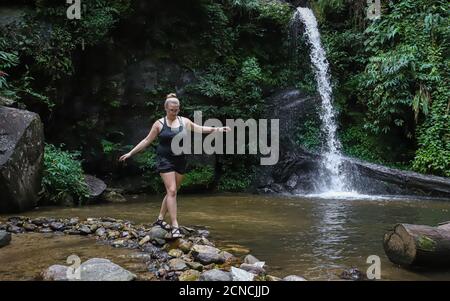 DOI SUTHEP-PUI NATIONAL PARK, THAILANDIA - 01 settembre 2019: Una donna cammina attraverso le pietre sul sentiero di fronte a Montha superiore che cascata nel nord Th Foto Stock