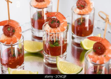 Antipasto di shish kebab con gamberi e chorizo salsicce con salsa barbecue in un bicchiere Foto Stock