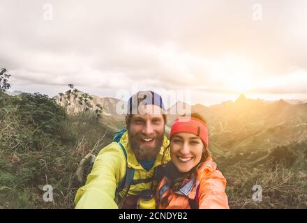 Felice coppia che prende selfie mentre fa trekking escursione sulle montagne - giovani escursionisti divertirsi esplorando la natura tour Foto Stock