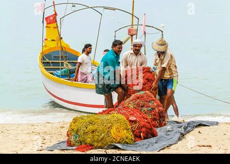 I pescatori che trasportano reti pesanti sulla spiaggia popolare Marari Beach, Mararikulam, Alappuzha (Alleppey), Kerala, India, Asia Foto Stock