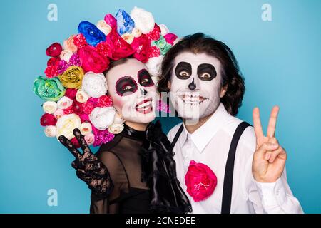 Foto di pauroso scricchioloso coppia uomo signora coccole spettacolo v-segno fare messaggio immagine soccoristi viventi indossare abito nero costume di morte fascia in rosa maschera Foto Stock