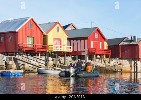 Persone che viaggiano in una barca di gomma alle boathouses su La costa della Norvegia Foto Stock