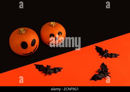 Zucche piccole con facce dipinte per Halloween e pipistrelli sopra sfondo arancione e nero Foto Stock