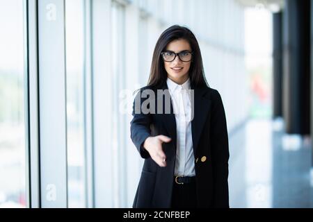 Giovane donna di affari pronta a handshake in piedi in ufficio Foto Stock