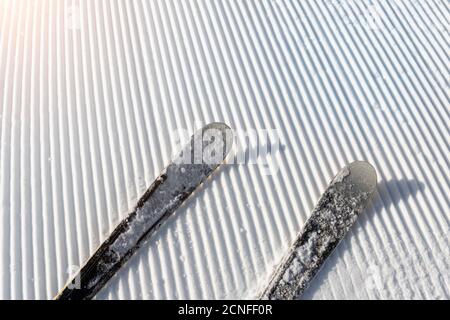 Punto panoramico delle gambe dello sciatore in discesa partenza in linea retta file di linee appena preparate piste da sci curate su bright giorno blu cielo sfondo Foto Stock