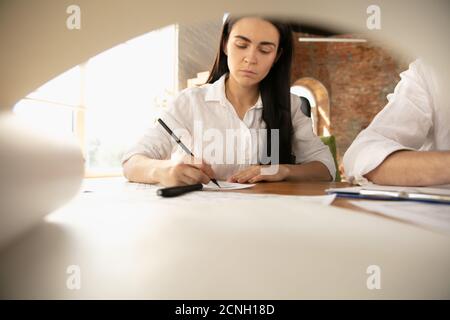 Giovane donna che ascolta l'architetto-ingegnere maschile presenta il progetto . Lavorare in ufficio con documenti, BluePrint. Primo concetto di casa, industriale, edilizia. Passaggio a un nuovo live place. Foto Stock