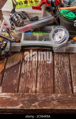 Diverse tegole da pesca con verga e bobine su sfondo marrone di legno. Mockap per la pubblicità e la pubblicazione. Foto Stock